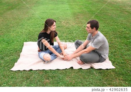 Young couple sit on a blanket on the grass 42902635