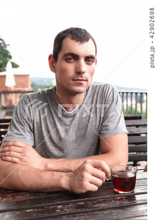 Young man holds cup of tea in a cafe Young man holds cup of tea in a cafe 42902698