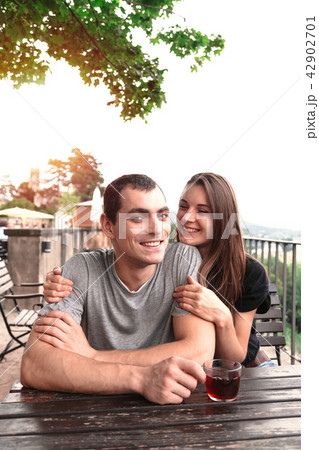 Young beautiful couple share tea at garden table Young beautiful couple share tea at garden table 42902701