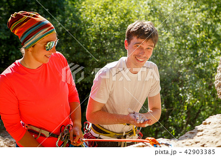 Photo of female climber in sunglasses and athlete's man with bag of talcum next to mountain 42903385
