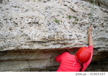 Photo from back of woman in helmet clambering over rock Photo from back of woman in helmet clambering over rock 42903387