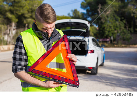 A man with a car gets an emergency sign 42903488