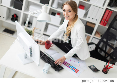 The young girl sat down on the desk in the office and worked with a computer and documents. The young girl sat down on the desk in the office and worked with a computer and documents. 42904100