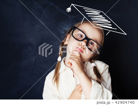 Pensive kid schoolgirl wearing graduation hat Pensive kid schoolgirl wearing graduation hat 42904740