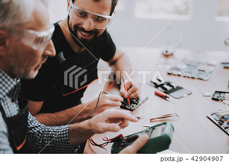 Two Men Repairing Hardware Equipment in Workshop. Two Men Repairing Hardware Equipment in Workshop. 42904907