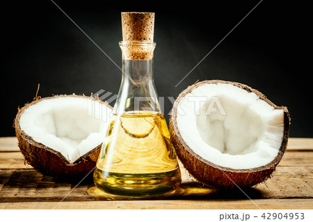 coconuts and a bottle of oil on a wooden table on a black background coconuts and a bottle of oil on a wooden table on a black background 42904953