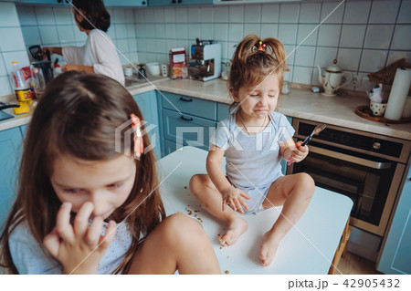 Two little girls in the kitchen sitting on the table. Two little girls in the kitchen sitting on the table. 42905432