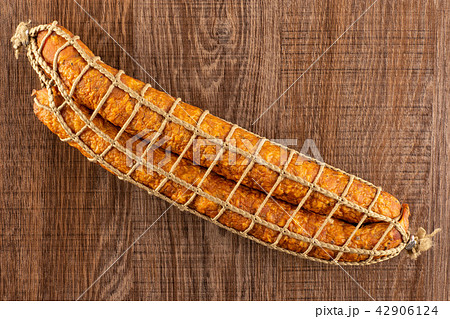 Dry smoked ham sausage on brown wood 42906124