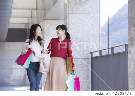 Two attractive young girls are doing shopping with shopping bags, walking and shopping outdoors. 005 Two attractive young girls are doing shopping with shopping bags, walking and shopping outdoors. 005 42908478