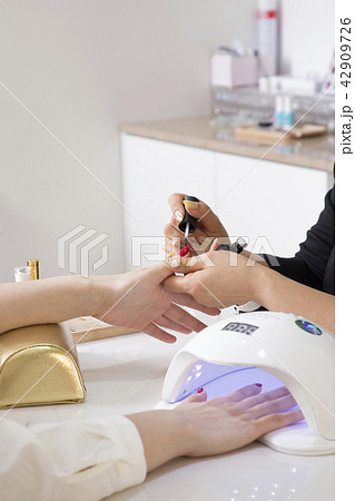 Nail salon woman hands treatment. Nail saloon woman painting color nail polish in hands stock photo. 059 42909726