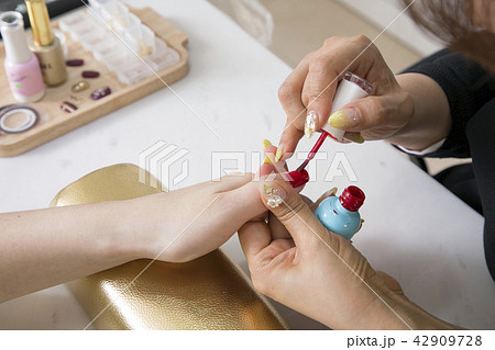 Nail salon woman hands treatment. Nail saloon woman painting color nail polish in hands stock photo. 057 42909728