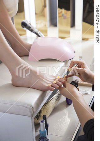 Pedicure treatment to woman feet in nails salon on sofa chair stock photo. 017 42909841