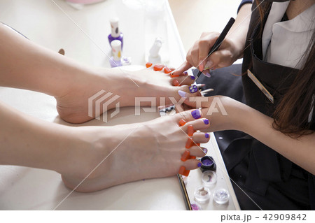 Pedicure treatment to woman feet in nails salon on sofa chair stock photo. 028 42909842
