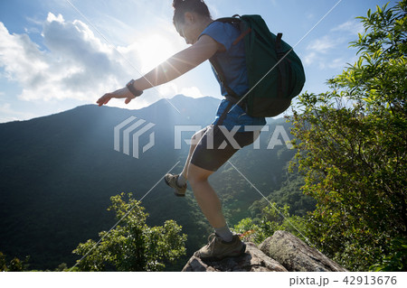 Woman hiker walking to the cliff edge  42913676