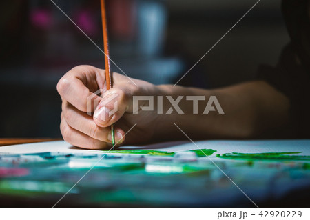 Woman hand using brush to paint on white paper 42920229