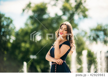 A girl is walking around the city, near a large fountain. Sunny day. Summer 42920981