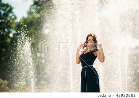 A girl is walking around the city, near a large fountain. Sunny day. Summer 42920983