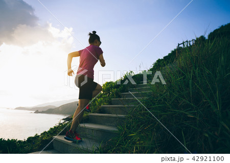Woman running up on seaside mountain stairs 42921100