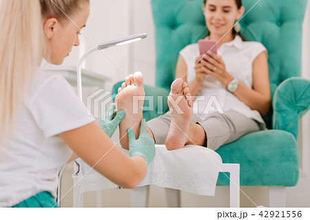 Blonde-haired chiropodist making feet massage for businesswoman Blonde-haired chiropodist making feet massage for businesswoman 42921556