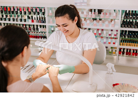 Beaming nail master laughing while talking to her pleasant client 42921842