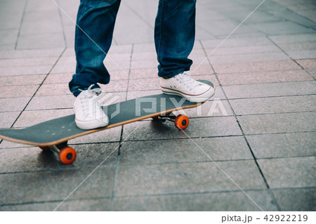 Skateboarder legs riding skateboard on city street Skateboarder legs riding skateboard on city street 42922219