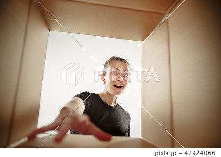 Woman unpacking and opening carton box and looking inside 42924066