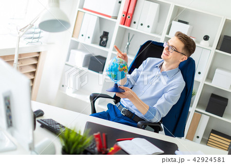 A young man sits in the office at the computer desk, closes his eyes and points a finger at the 42924581