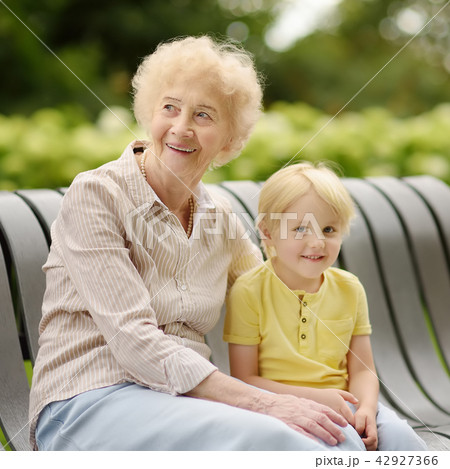 Beautiful granny and her little grandson walking together in park Beautiful granny and her little grandson walking together in park 42927366