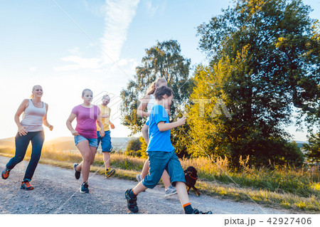 Playful family running and playing on a path in summer landscape Playful family running and playing on a path in summer landscape 42927406