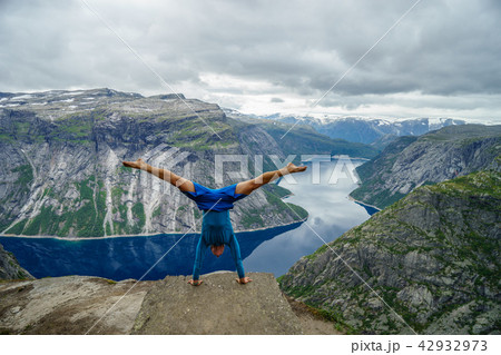Gymnast standing on his hands on the edge with fjord on background near Trolltunga. Norway Gymnast standing on his hands on the edge with fjord on background near Trolltunga. Norway 42932973