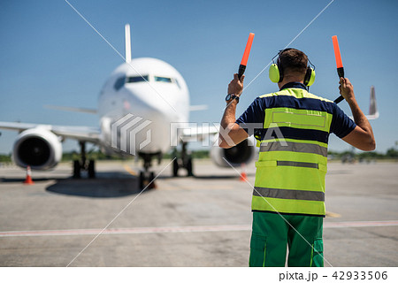 Airport worker in headphones meeting passenger plane 42933506