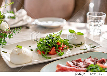 Italian Caprese salad. burrata cheese, tomatoes and basil herb leaves. Balsamic vinegar arranged on Italian Caprese salad. burrata cheese, tomatoes and basil herb leaves. Balsamic vinegar arranged on 42943175