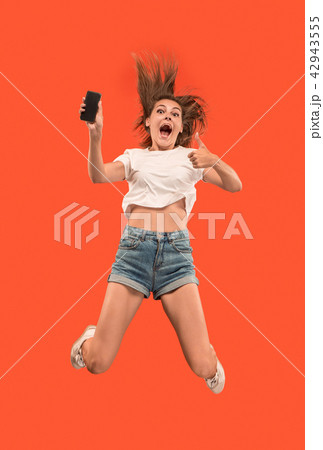 Full length of pretty young woman with mobile phone while jumping 42943555