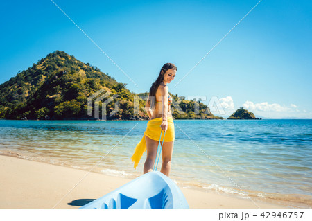 Woman dragging her boat to the water on the beach 42946757