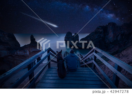 Man with dog looking at Milky Way on the beach Man with dog looking at Milky Way on the beach 42947278