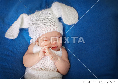 newborn baby in a hat with ears on a blue 42947927