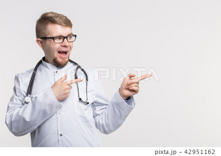 Happy young doctor in studio pointing left Happy young doctor in studio pointing left 42951162