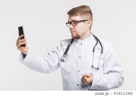 Young male doctor making photo on his phone Young male doctor making photo on his phone 42951200