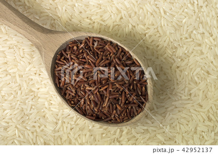 Red rice in wooden spoon on white rice background Red rice in wooden spoon on white rice background 42952137