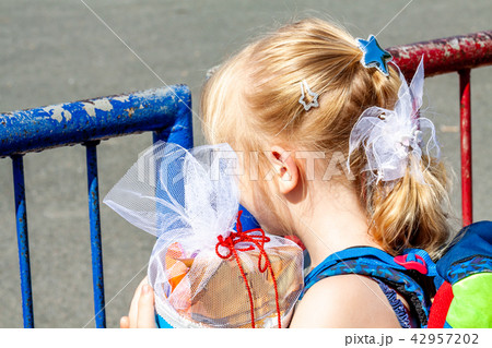 Little girl standing in front of the school building holding her candy cone Little girl standing in front of the school building holding her candy cone 42957202