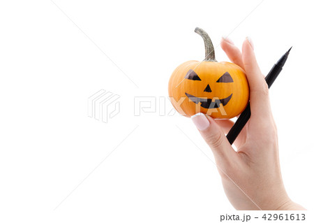Woman's hand holding small halloween pumpkin and marker pen Woman's hand holding small halloween pumpkin and marker pen 42961613