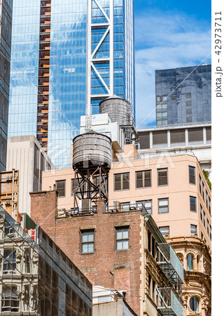 Water towers on rooftop of old buildings against modern skyscrap Water towers on rooftop of old buildings against modern skyscrap 42973711