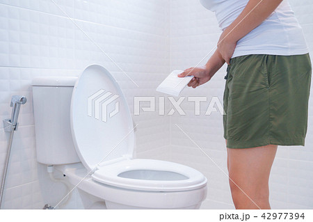 Woman holding sanitary napkins in font of toilet Woman holding sanitary napkins in font of toilet 42977394