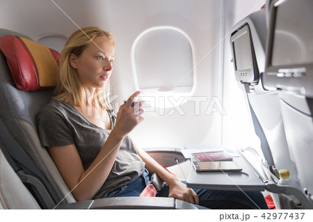 Woman drinking coffee on commercial passengers airplane during flight. Woman drinking coffee on commercial passengers airplane during flight. 42977437