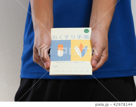 おくすり手帳を持つ男性の手元 42978144