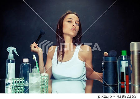 Beauty woman applying makeup. Beautiful girl looking in the mirror and applying cosmetic with a big Beauty woman applying makeup. Beautiful girl looking in the mirror and applying cosmetic with a big 42982265