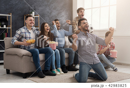 Happy friends watching football match at home Happy friends watching football match at home 42983825