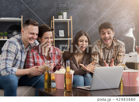 Happy friends sitting on sofa and watching comedy movie 42983880