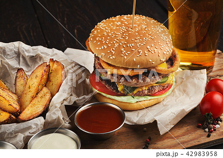 Burger and potatoes served with beer at restaurant, closeup 42983958