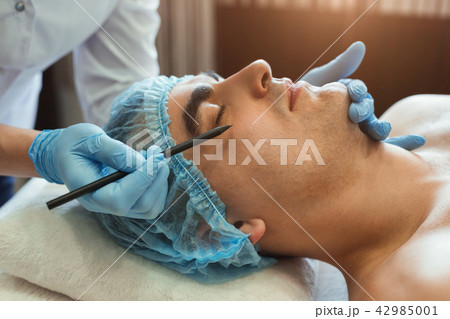 Female gands in gloves marking man face 42985001
